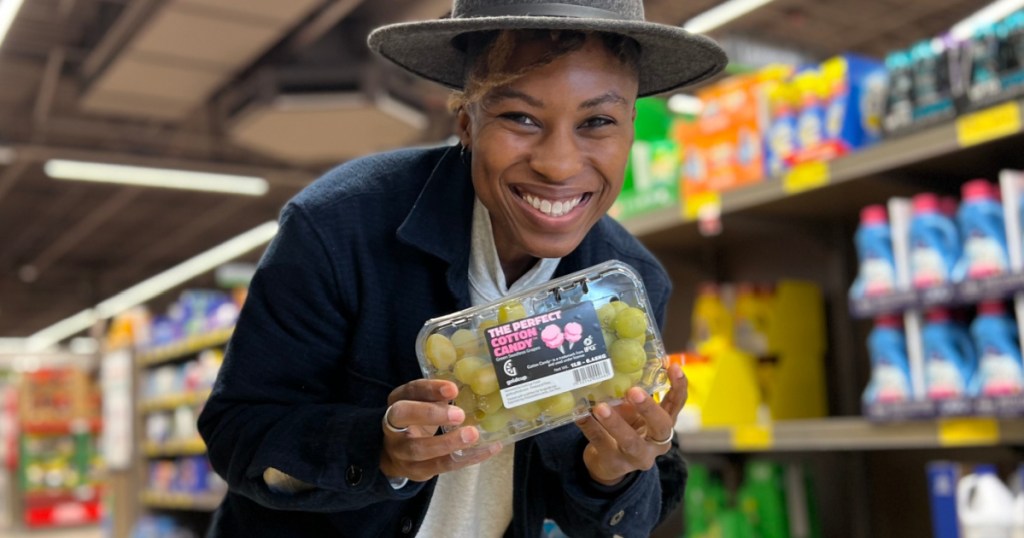 woman holding container of cotton candy grapes in store
