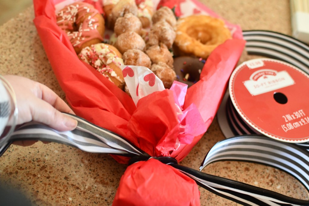 Adding ribbon to a donut bouquet of donut flowers