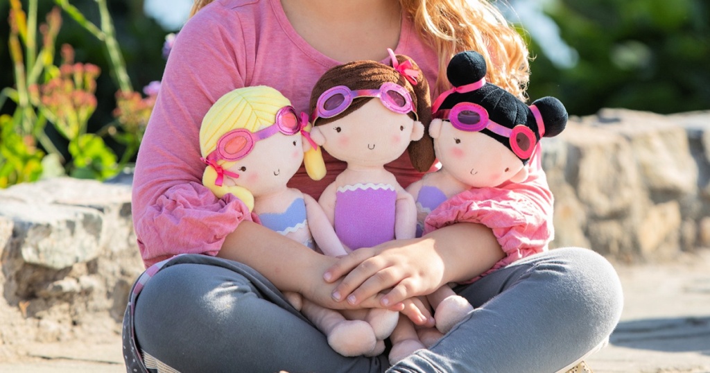 girl holding three dolls