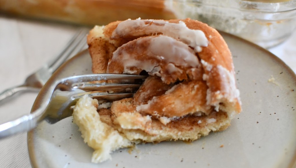 Using a fork to eat a cinnamon roll