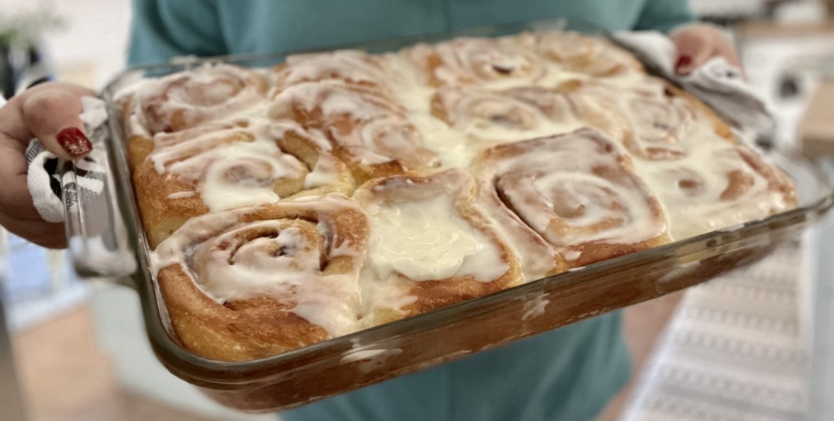 Woman holding a pan of Cinnamon Rolls, made with the Rhodes cinnamon rolls hack 