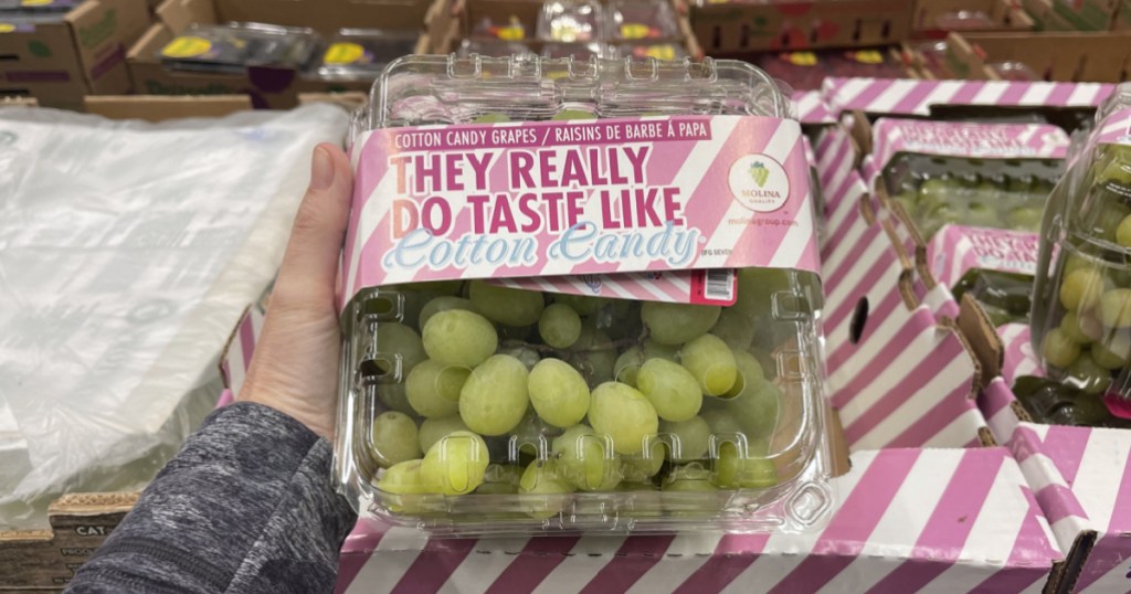 hand holding large package of cotton candy grapes in store