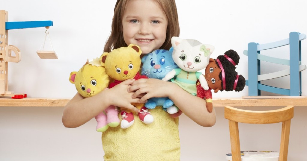 girl holding five plush toys in playroom