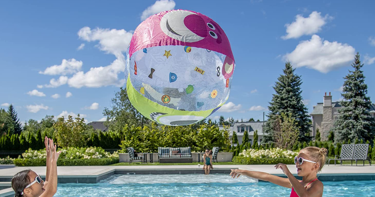 two girls playing with giant inflatable beach ball in pool