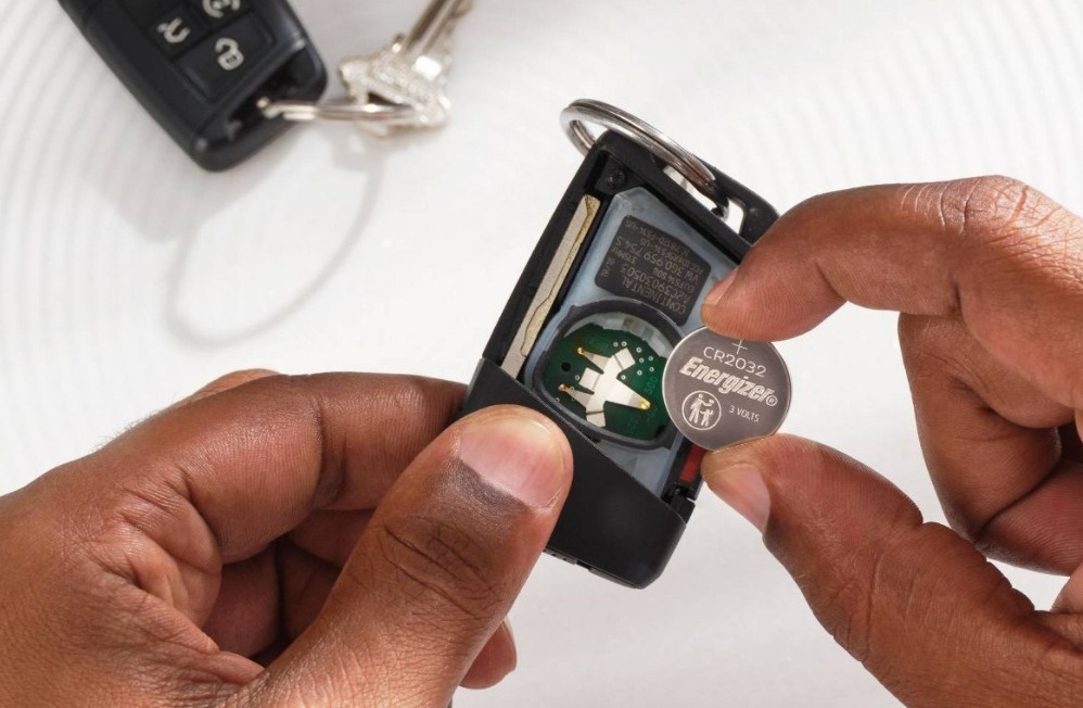 hands putting a battery in a car key fob
