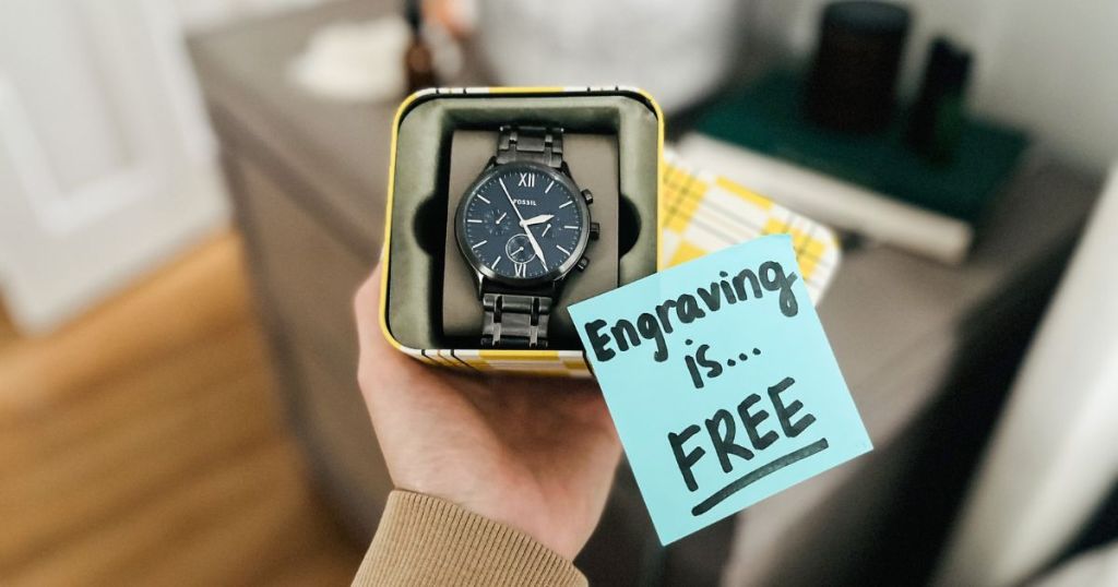 person holding box with Fossil Watch and blue post it note reading "Engraving is FREE"
