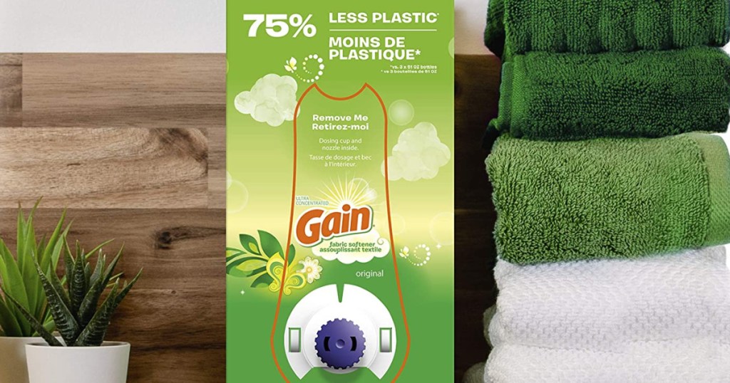 Gain detergent Eco-Box sitting on a shelf between plants and stacked, folded towels