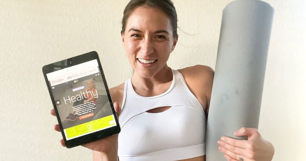 woman holding an ipad and a yoga mat