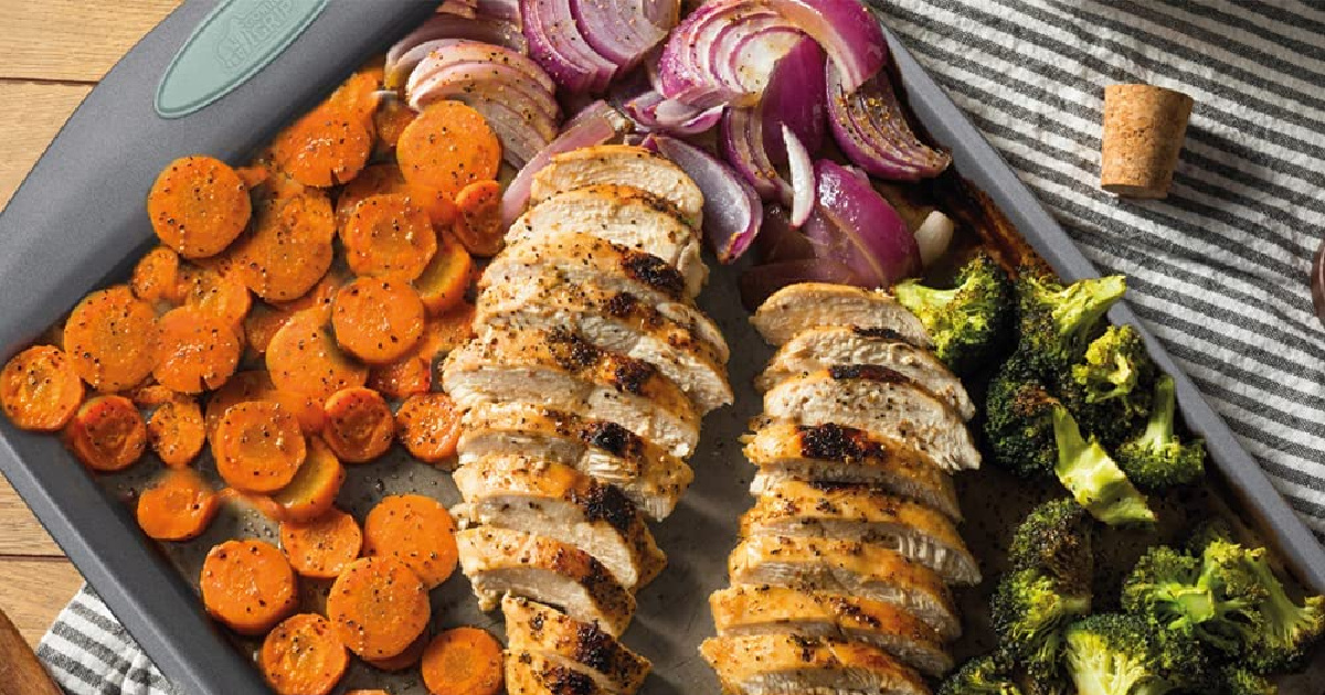 large sheet pan with cooked chicken and veggies on wood counter