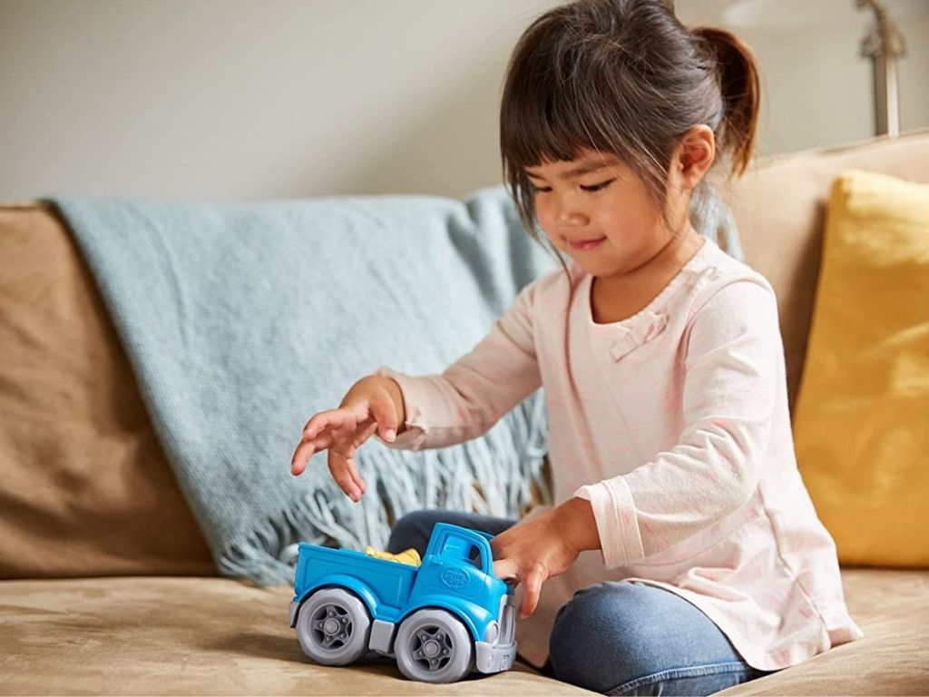 girl playing with blue Green Toys pickup truck