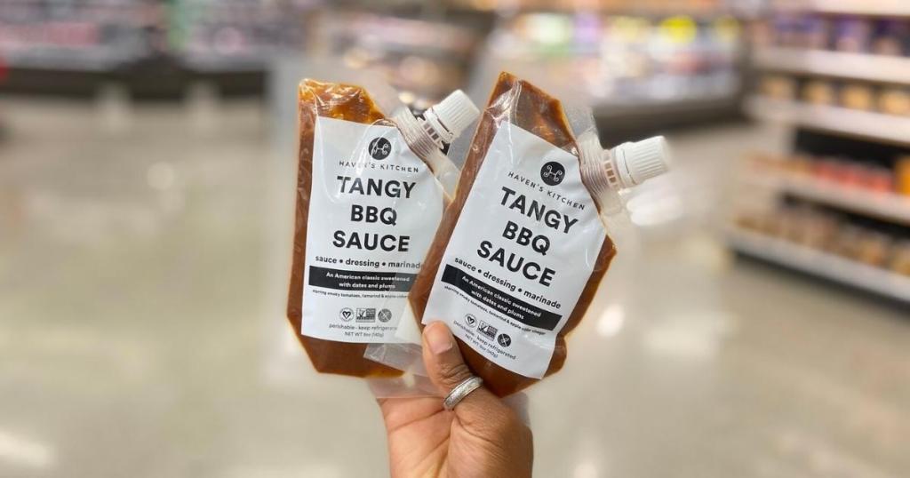hand holding haven's kitchen tangy plant based bbq sauce in store