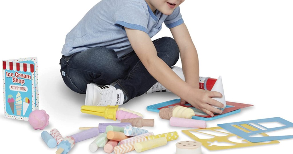 child playing with chalk set on white background