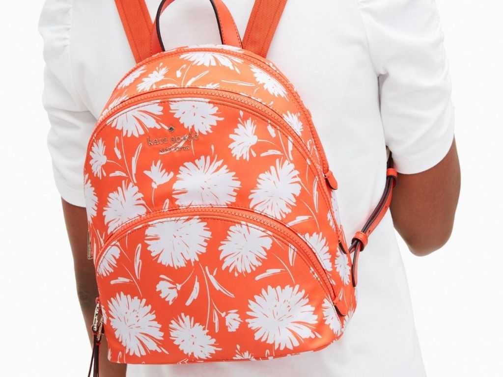 woman wearing coral and white floral Kate Spade backpack