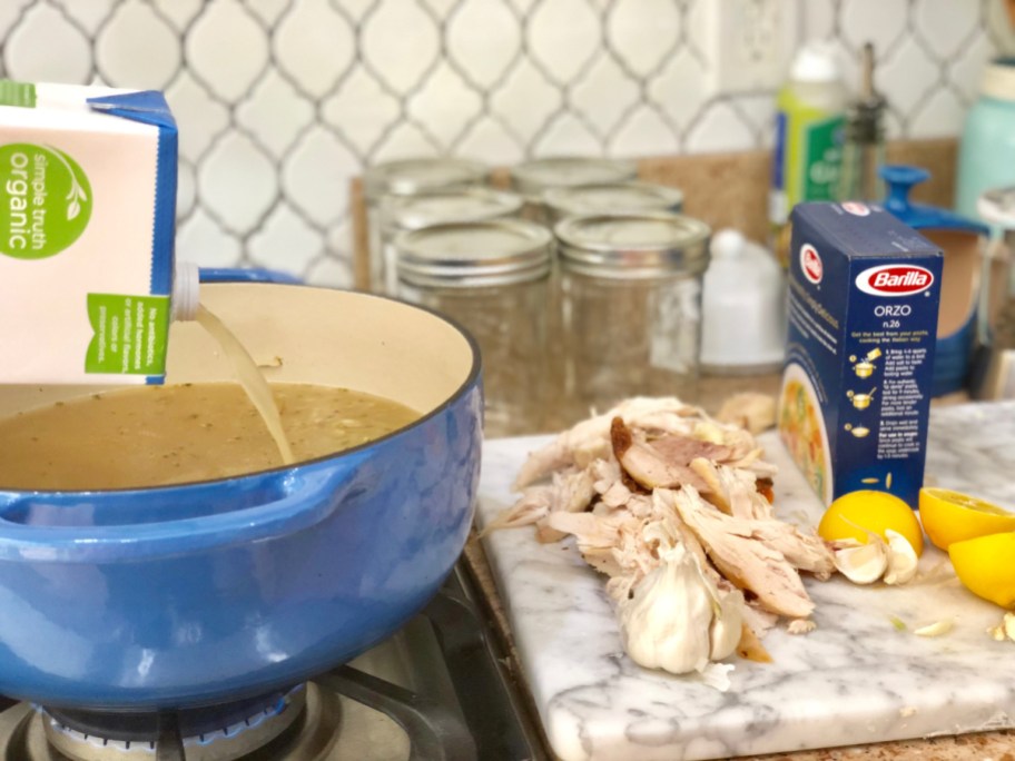 Pouring broth into a saucepan to make chicken lemon orzo soup and show how to freeze soup in mason jars