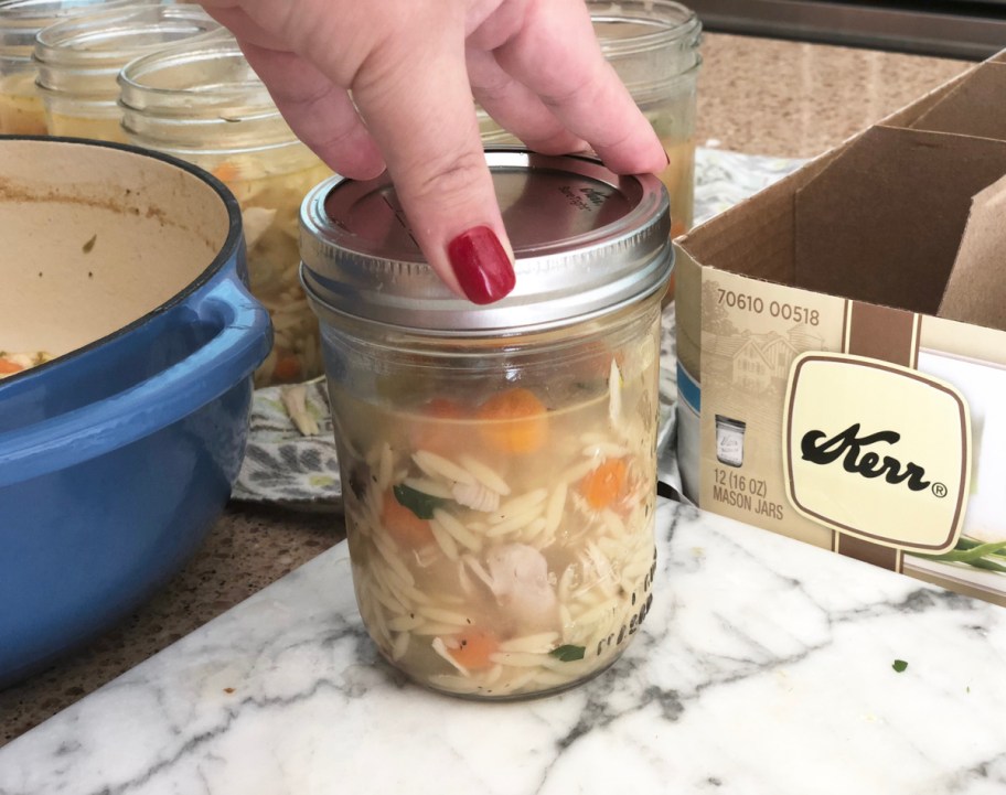 Hand placing a lid on Mason Jar Soup