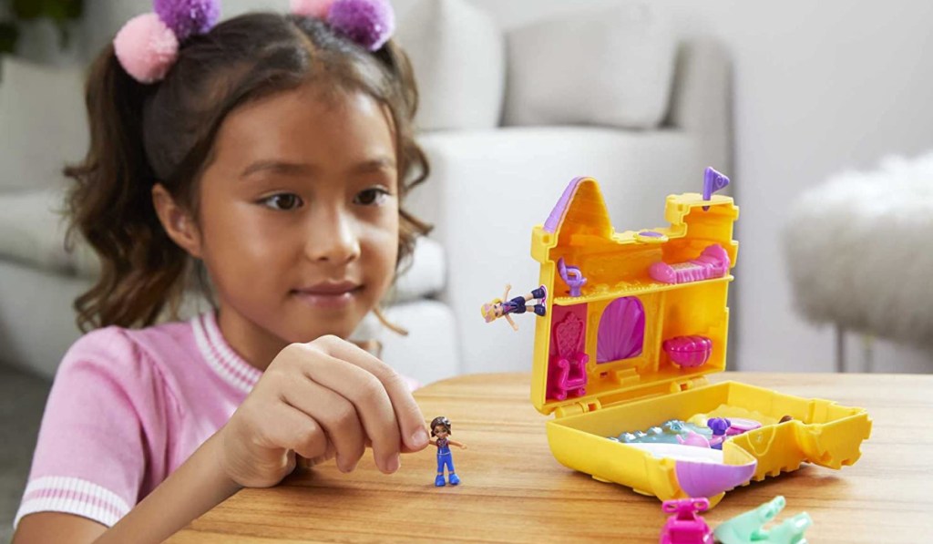 girl playing with a polly pocket sandcastle set