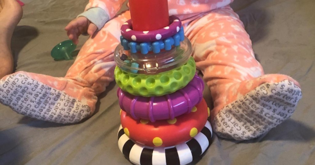 child's feet next to stacking toy on carpet