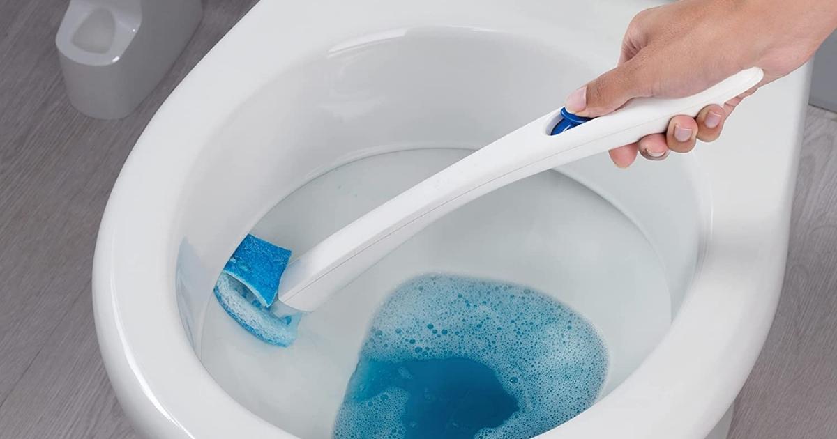 hand using a scotch brite toilet bowl scrubber to clean the toilet