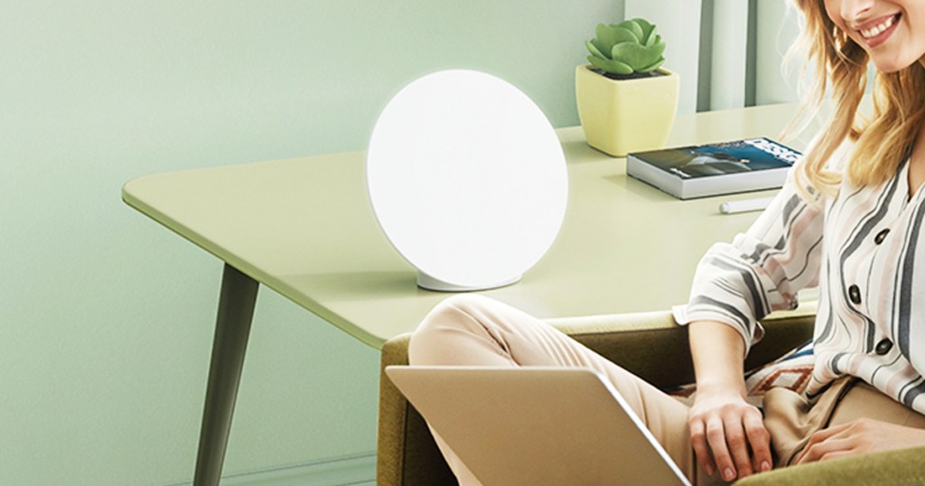 woman on laptop near light therapy lamp