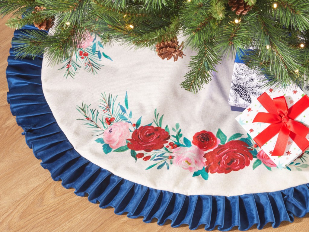 تنورة شجرة عيد الميلاد ذات الكشكشة الزرقاء والورود الحمراء من بايونير وومن معروضة على الأرض مع الهدايا حولها