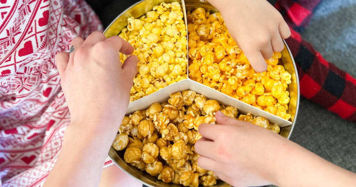 kids hands grabbing popcorn from a tin