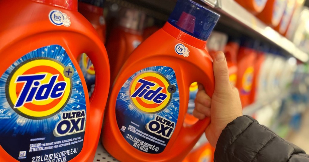 hand pulling Tide Ultra Oxi Detergent off shelf