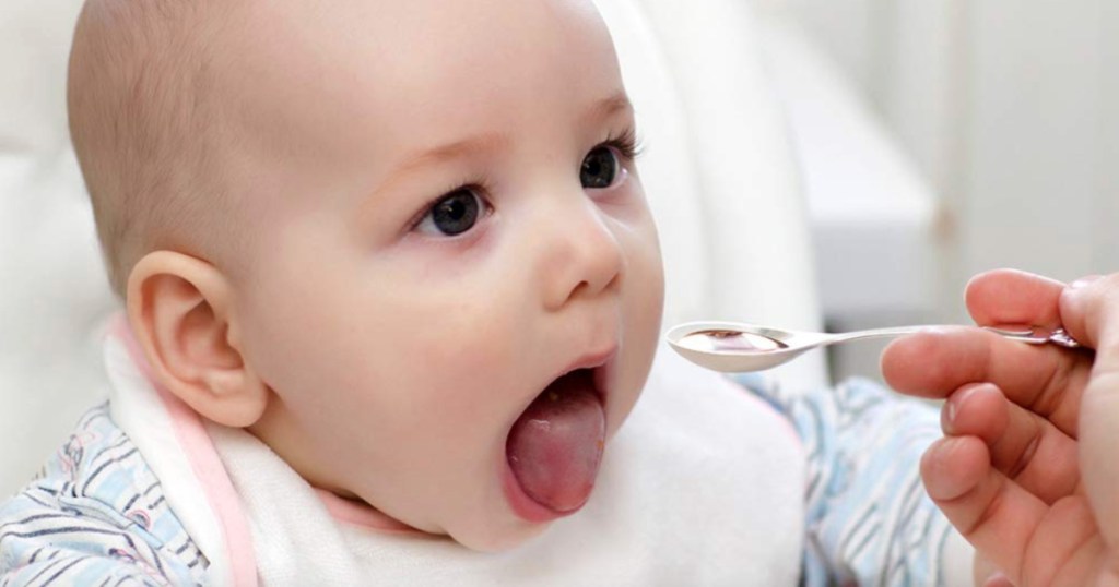baby with open mouth eating from spoon