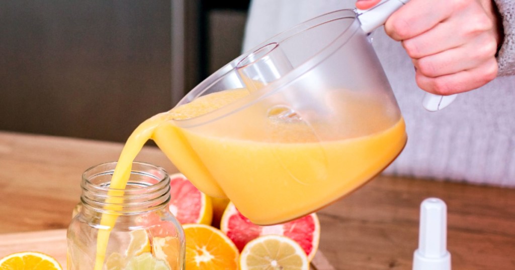 person pouring orange juice from a juicer