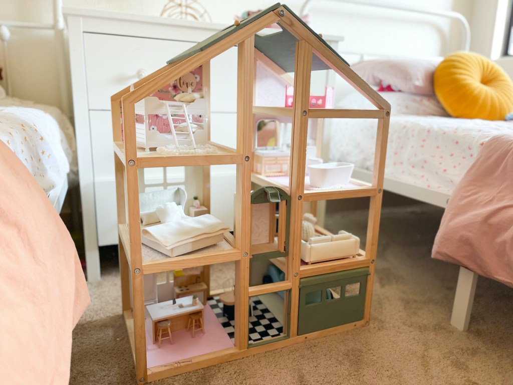 close up of wooden dollhouse sitting on floor in girls room