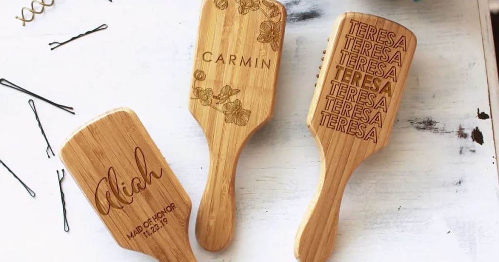 three wooden hairbrushes with personalized messages on them