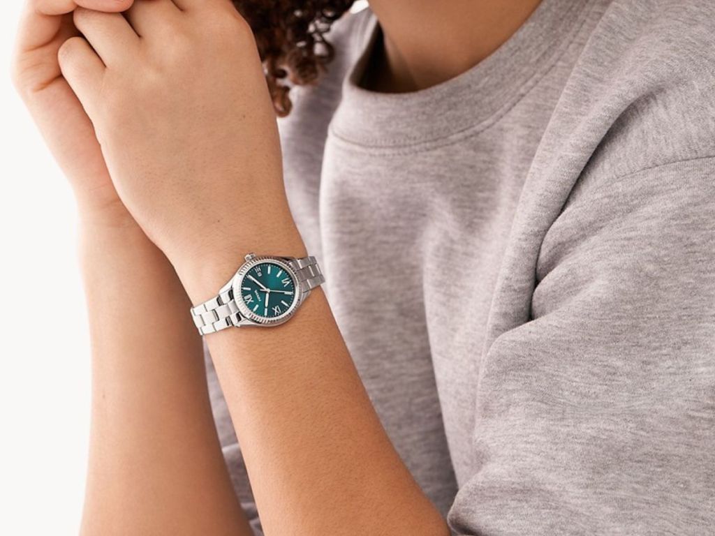 person wearing Fossil watch with silver band and green face