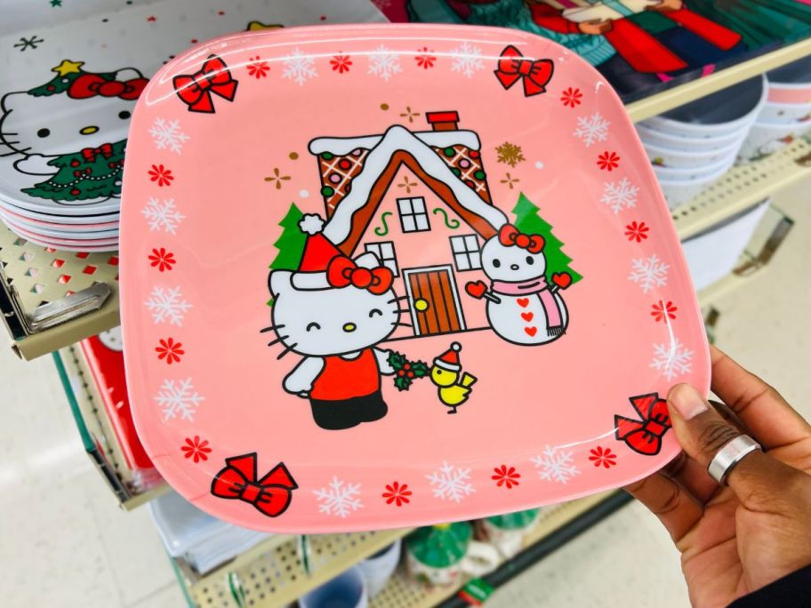 a womans hand holding a holiday hello kitty dinner plate