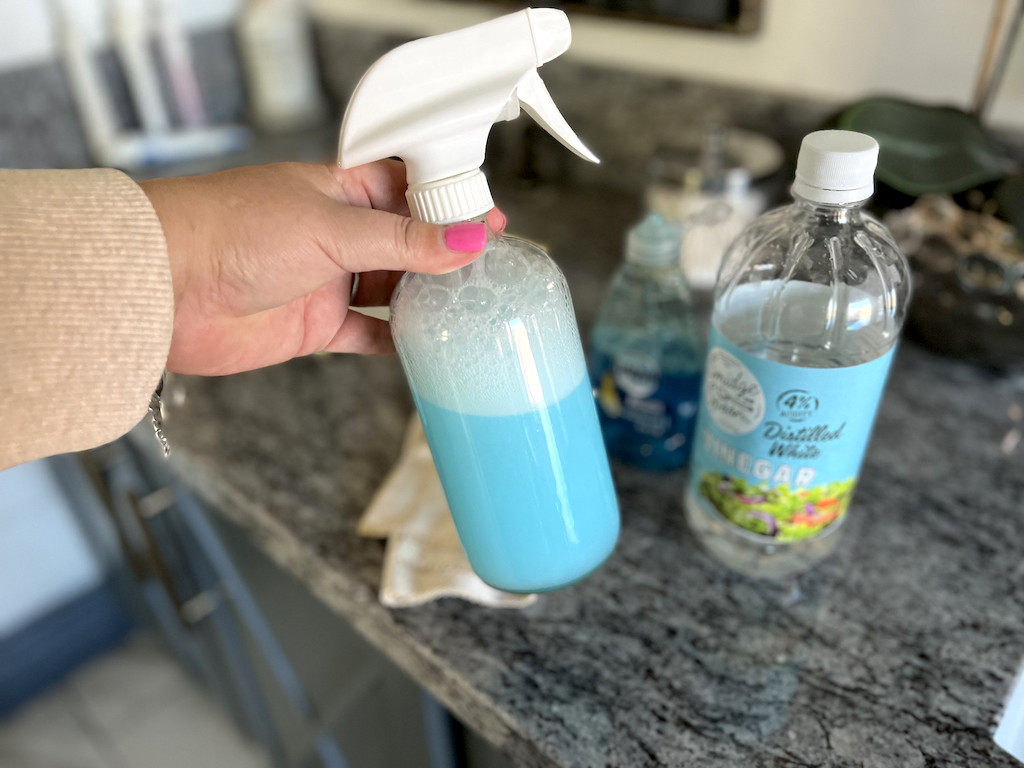 holding DIY shower cleaner in spray bottle 