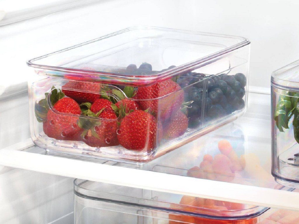 strawberries and blueberries in clear storage bin in fridge