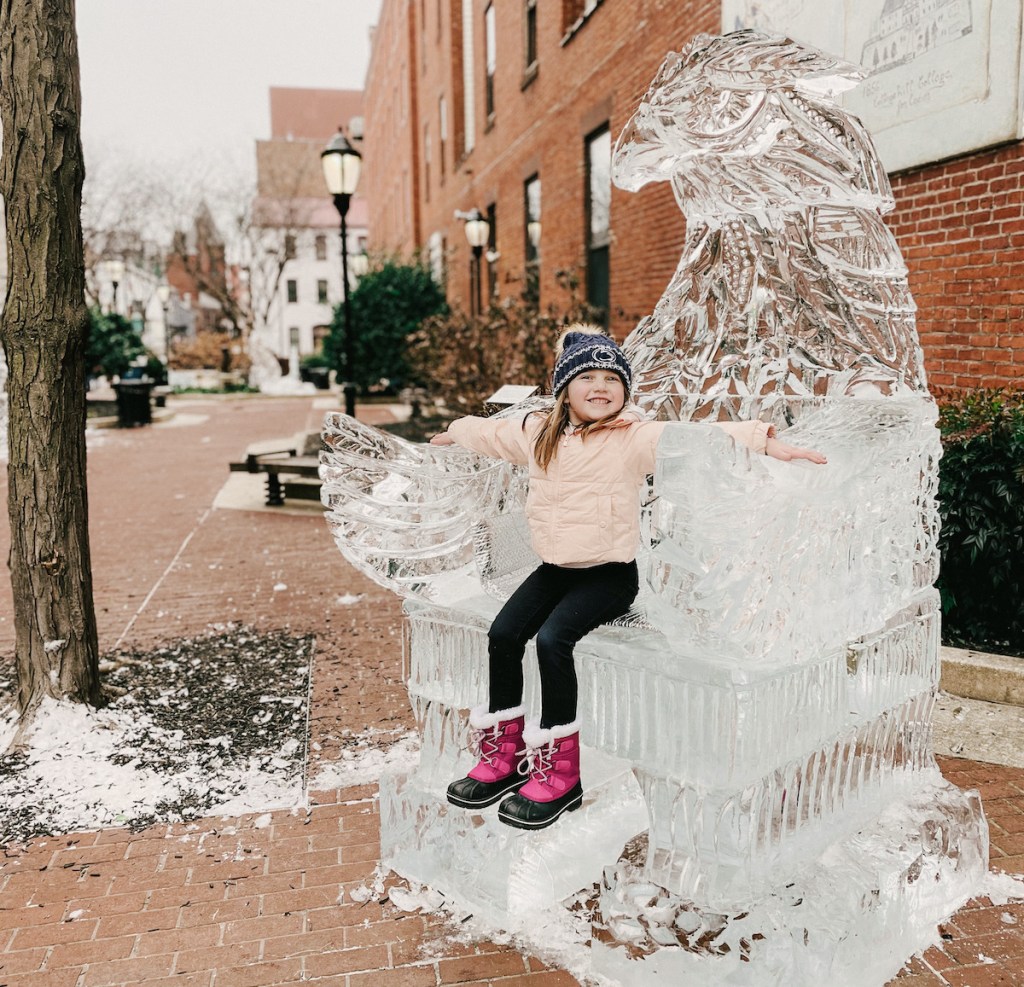 girl sitting on huge bald eagle ice sculpture