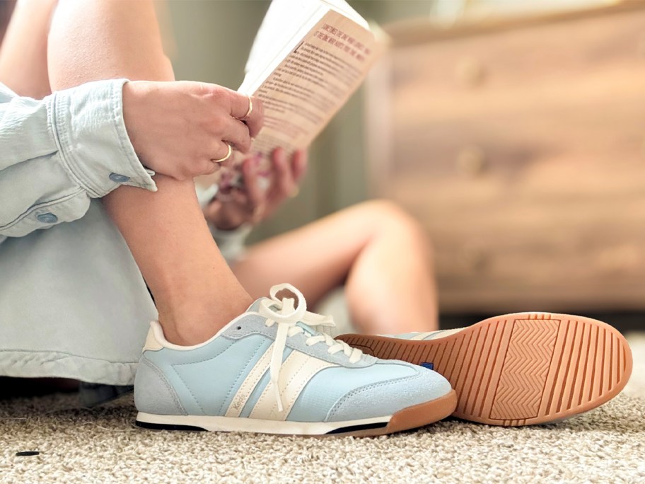 person sitting on ground wearing blue keds shoes 