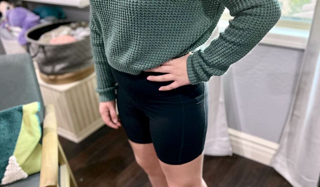 girl wearing black biker shorts with green knit sweater