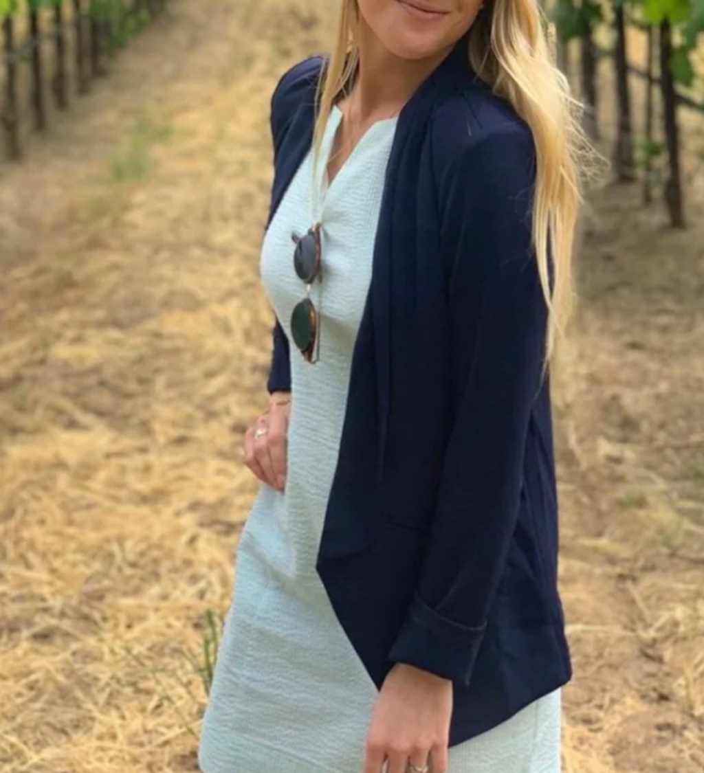 woman standing outside in vineyard wearing dress and navy blazer