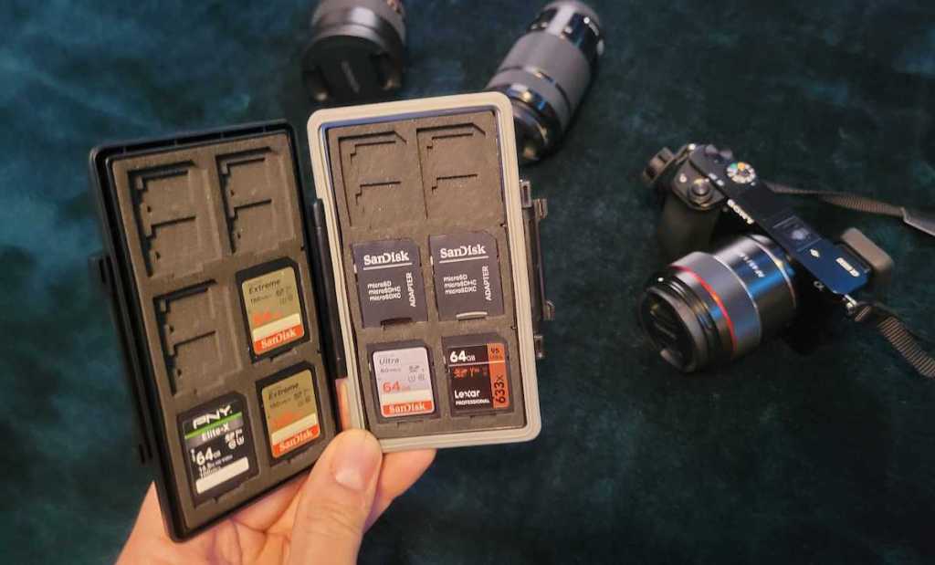 hand holding memory card case over camera and lenses