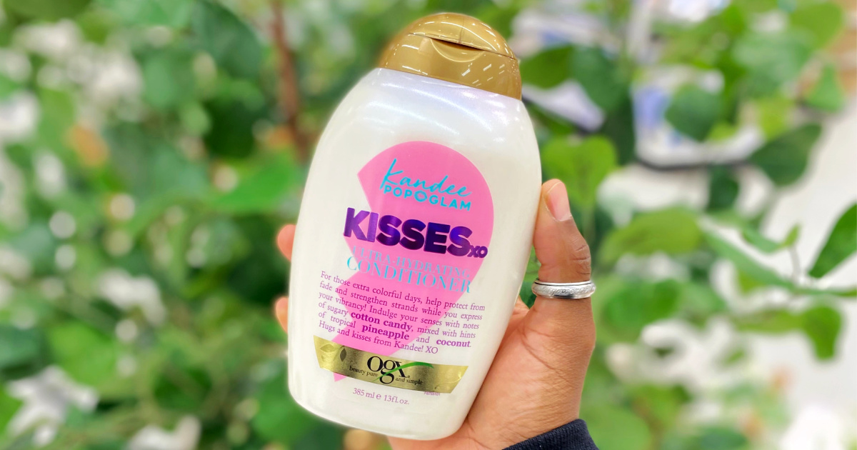 hand holding up a bottle of ogx kisses conditioner
