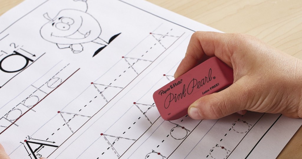 child holding a lrge pink eraser on top of a worksheet