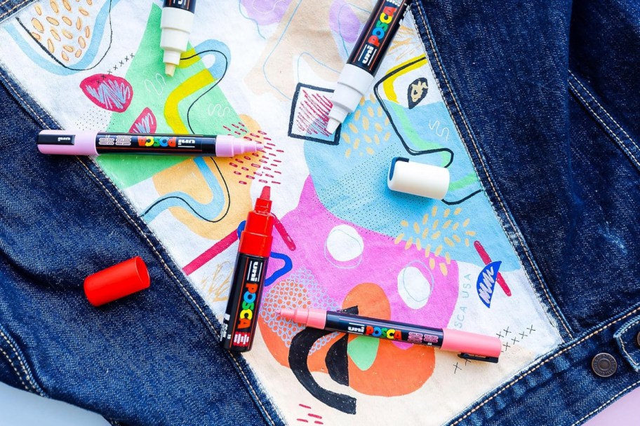 posca paint markers laid across colorfully illustrated fabric