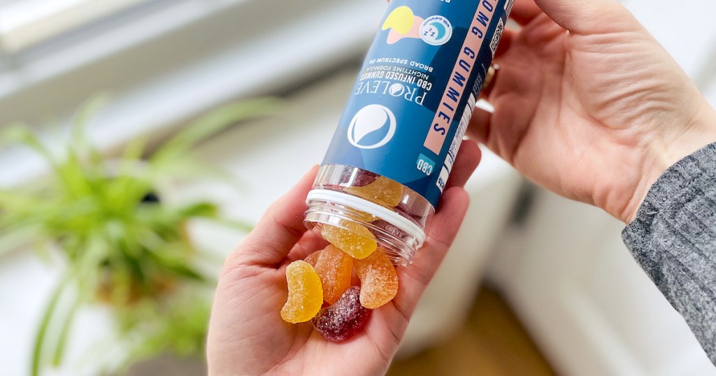 hand pouring candy cbd gummies into palm of hand in front of window