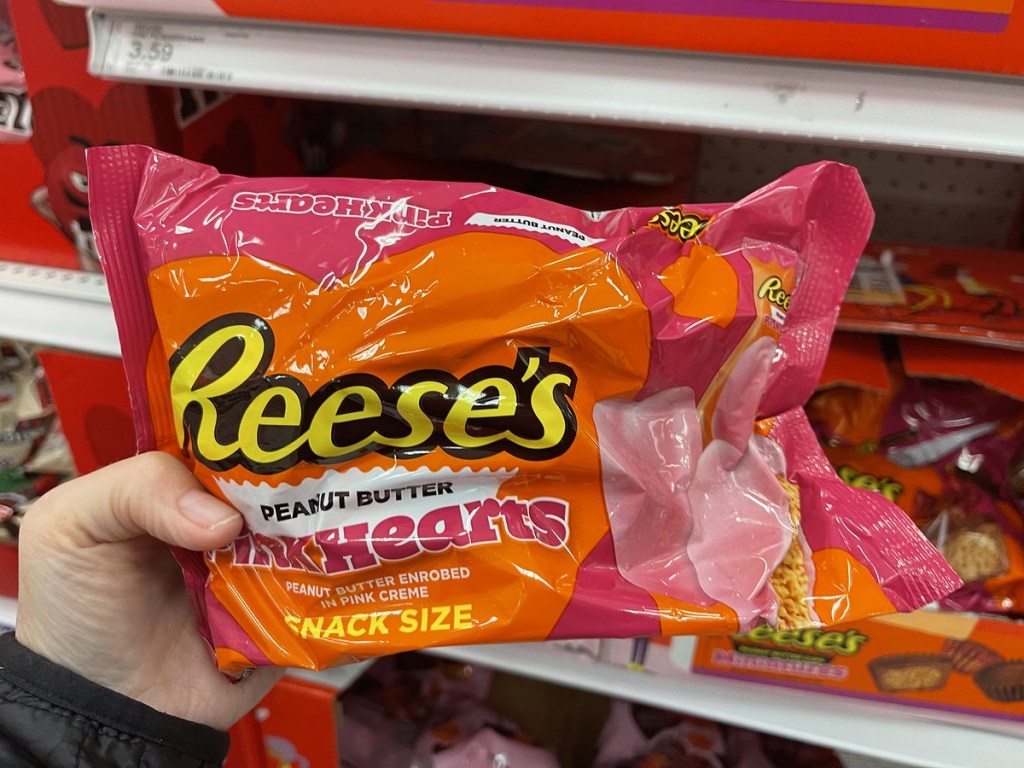 holding a bag of Reese's Pink Hearts