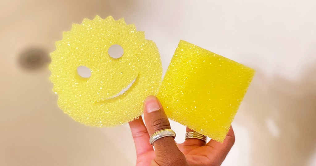 hand holding two yellow scrubbing sponges