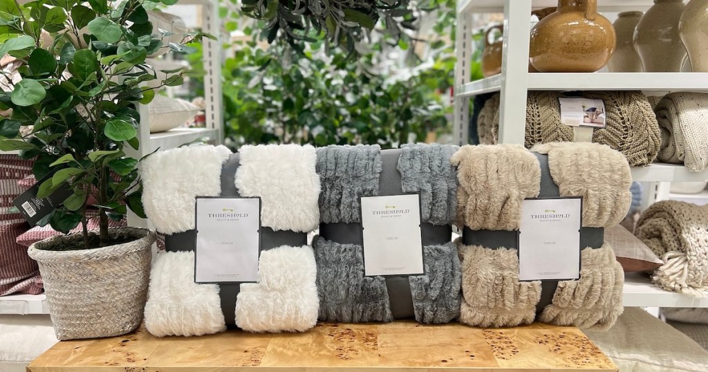 various faux fur throw blankets with threshold packaging on wood table