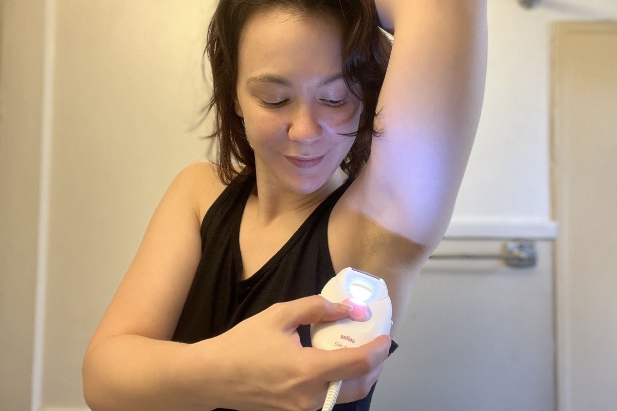 woman using epilator shaving attachment on underarms