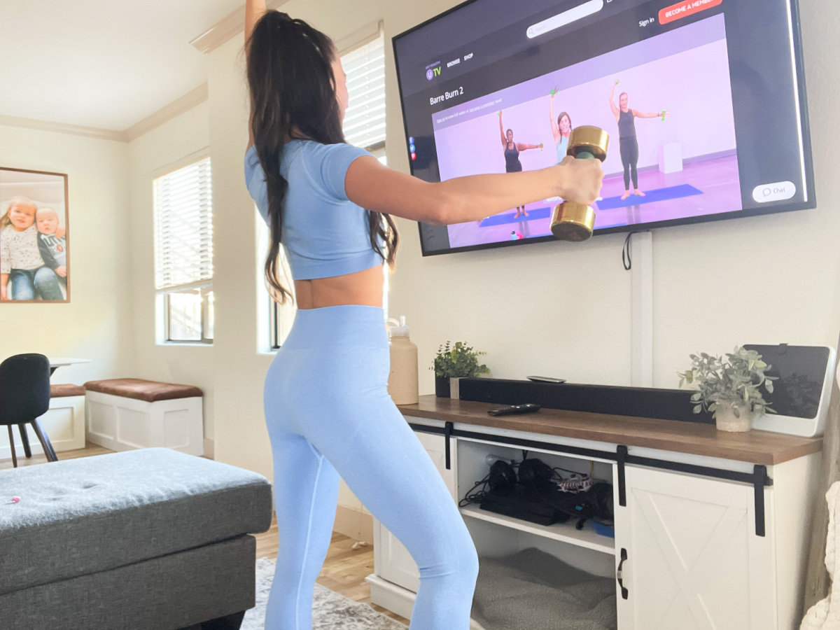 woman holding weights in front of TV