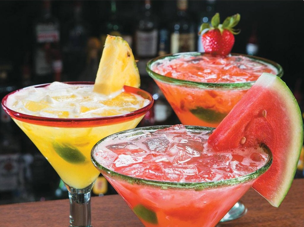 3 margaritas garnished with different fruits