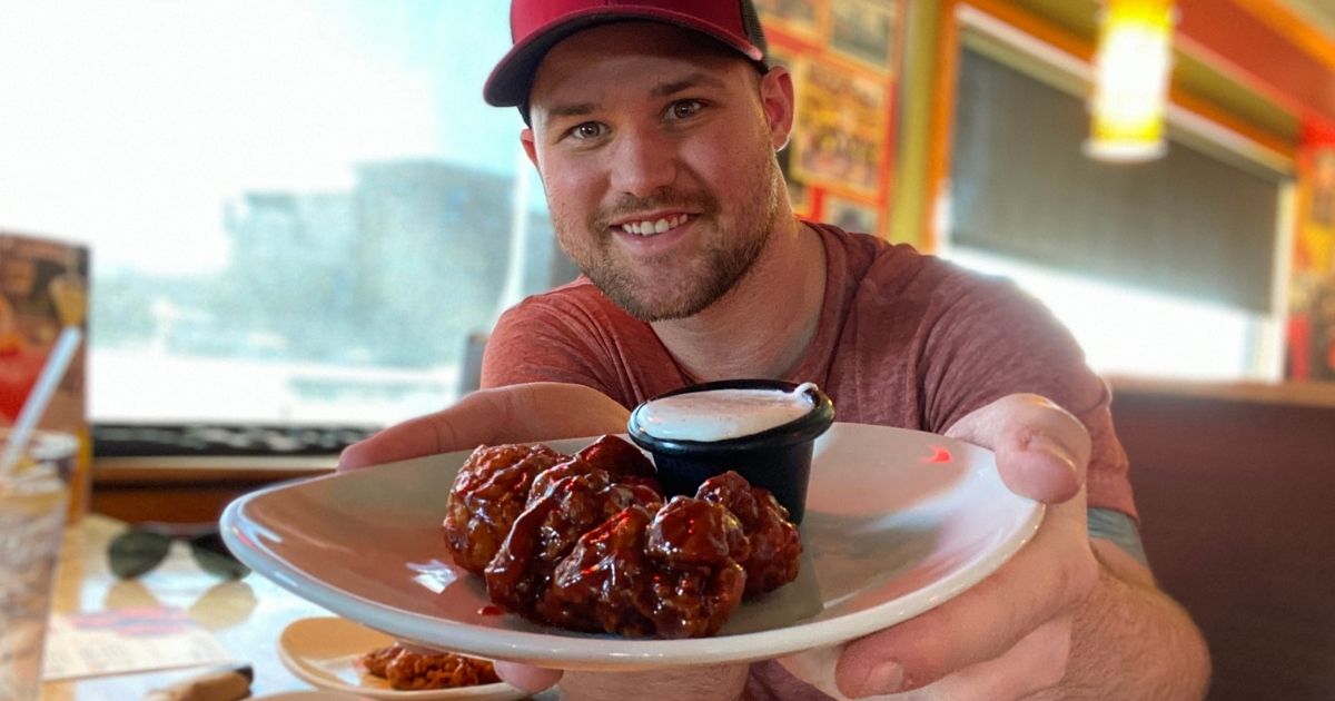 man holding a plate of Applebee's wings